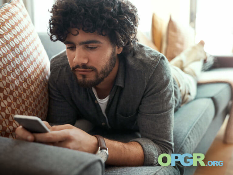 person laying on couch looking at cell phone