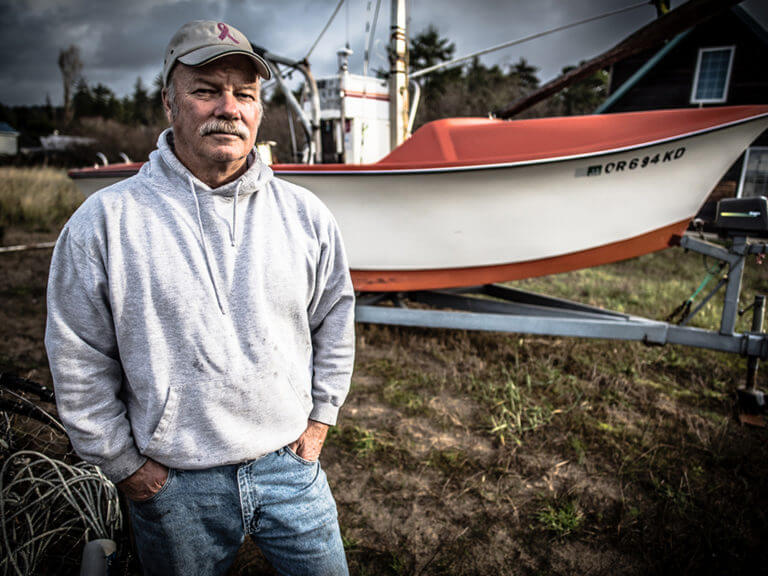 A man stands in front of a boat on a trailer