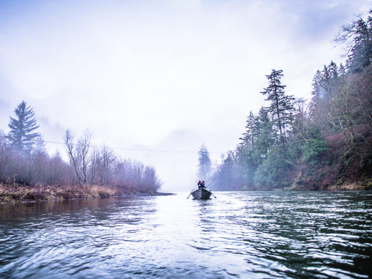 A man in a boat fishing on a river