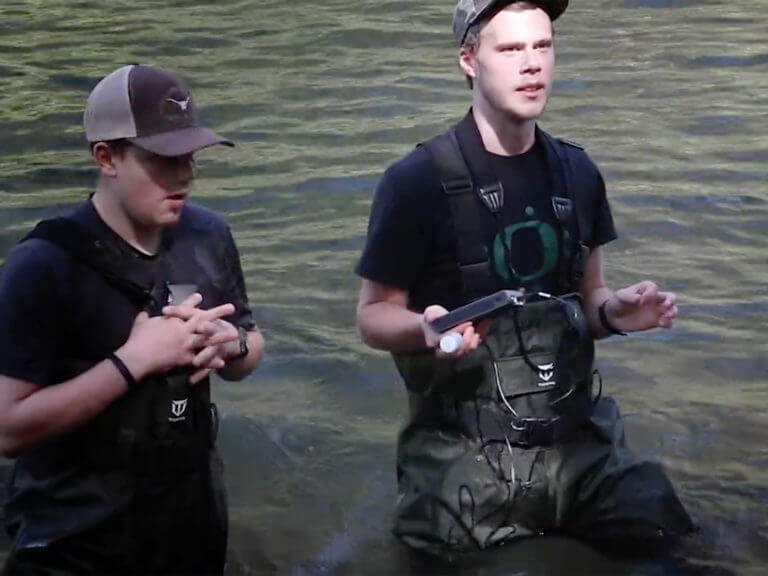 students standing in creek in waders